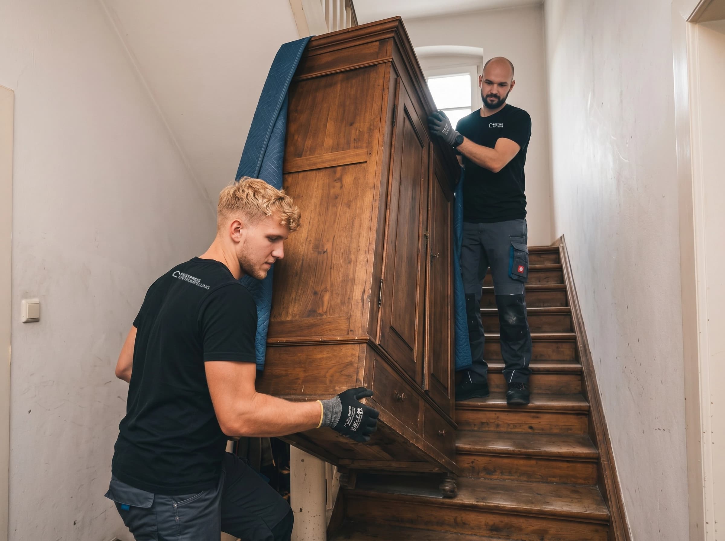 Team trägt schweren Wandschrank die Treppe hinunter in Dresden