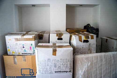 Viele Umzugskartons und verpackte Möbel — typischer Aufwand beim Selber-Beräumen
